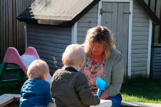En voksen leger med to børn udenfor
