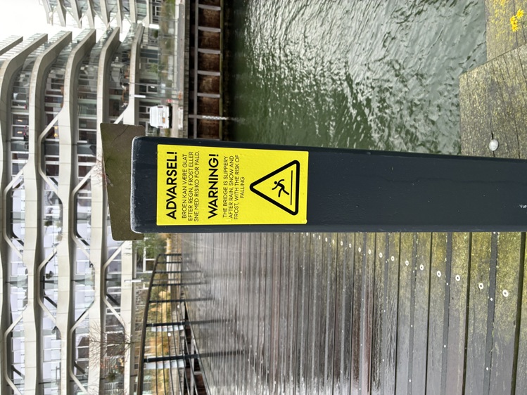 Klistermærke med advarsel på stolpe ved bro