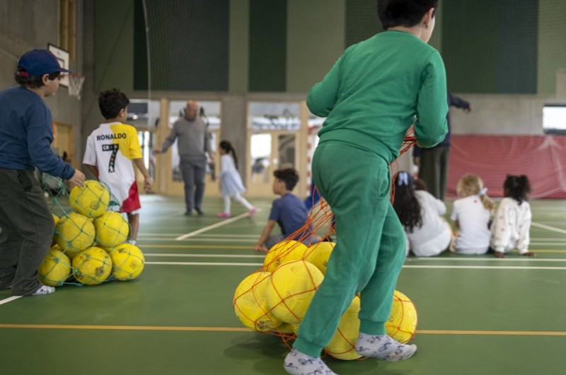 Dreng i grøn træningsdragt  løber med net fyldt med gule fodbolde