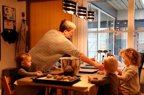 En voksen og nogle børn bager boller