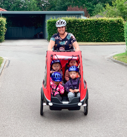 En voksen med fire børn i ladcyklen