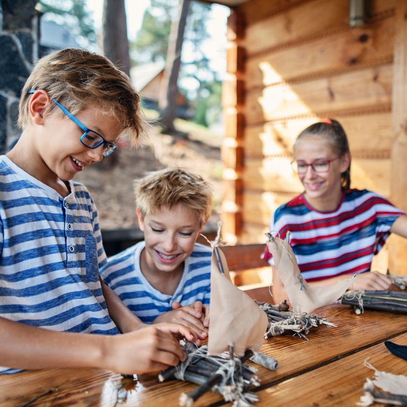 Tre børn bygger små tømmerflåder