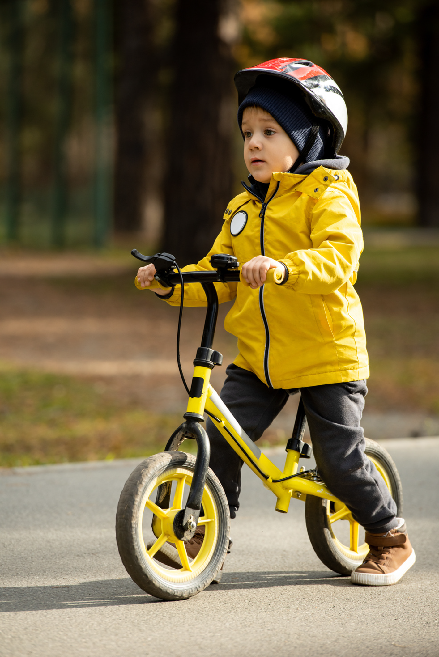 Barn i en gul jakke på en løbecykel