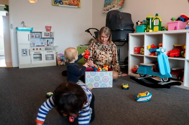 En voksen leger med to børn på legeværelset