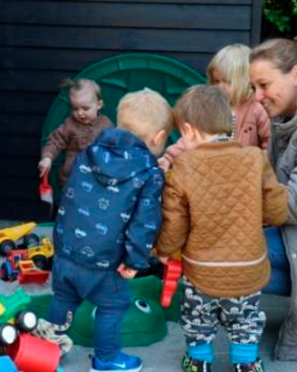 En voksen og fire børn leger udenfor