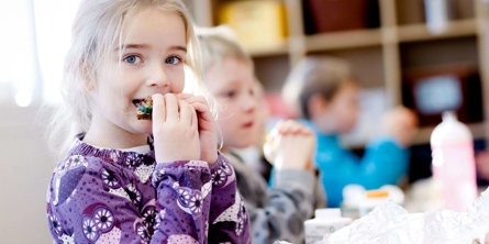 En pige spiser sin madpakke i klassen