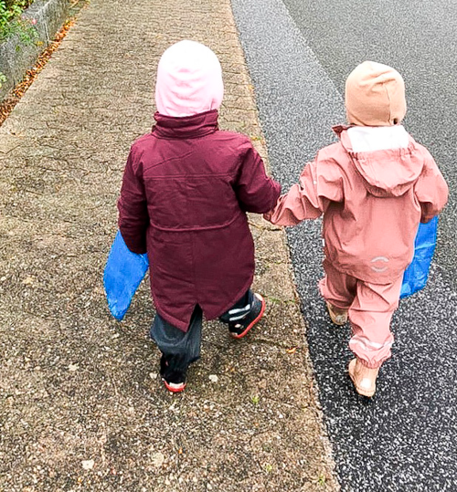 To børn i flyverdragter går med hinanden i hånden