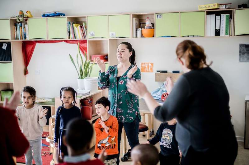 Kvindelige pædagoger leger sangleg med børnehavebørn