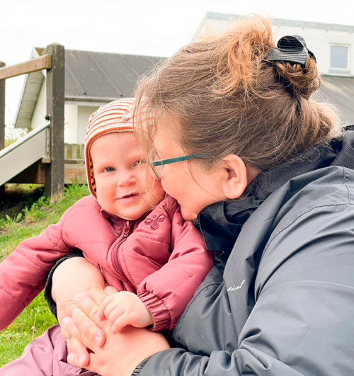 En dagplejer sidder med et barn udenfor