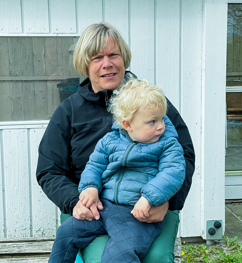 Voksen med barn på skødet på legepladsen
