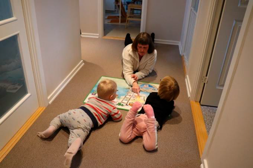 En voksen og to børn læser i en billedbog