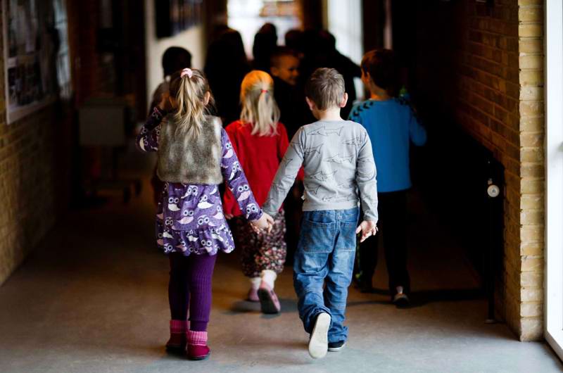 To skolebørn hånd i hånd på gangen