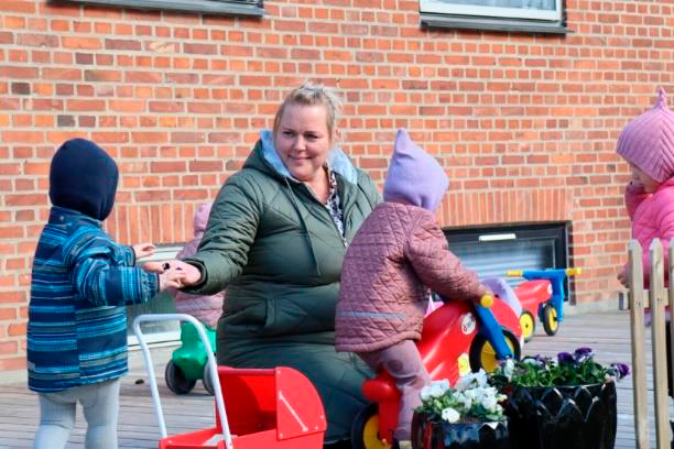En voksen og fire børn leger udenfor